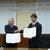 協定書に調印して握手する濱元理事長（左）と久保田局長