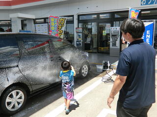 洗車体験をする子どもを見守る洗車スタッフの佐々木さん