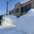 雪に埋まった福井県石油会館の玄関を除雪する事務局員(９日午後１時・福井市内)